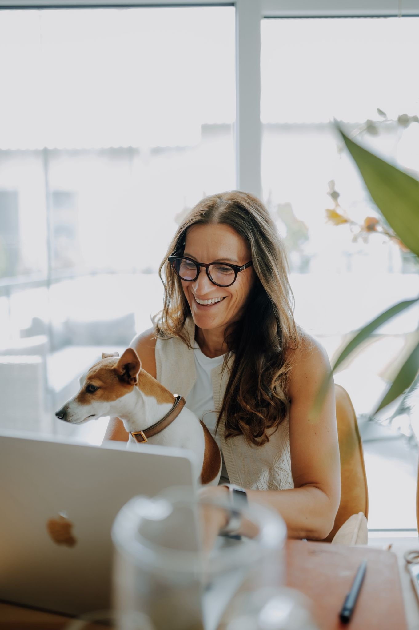 Nada Kammerer lächelt am Laptop, ihr Hund sitzt bei ihr